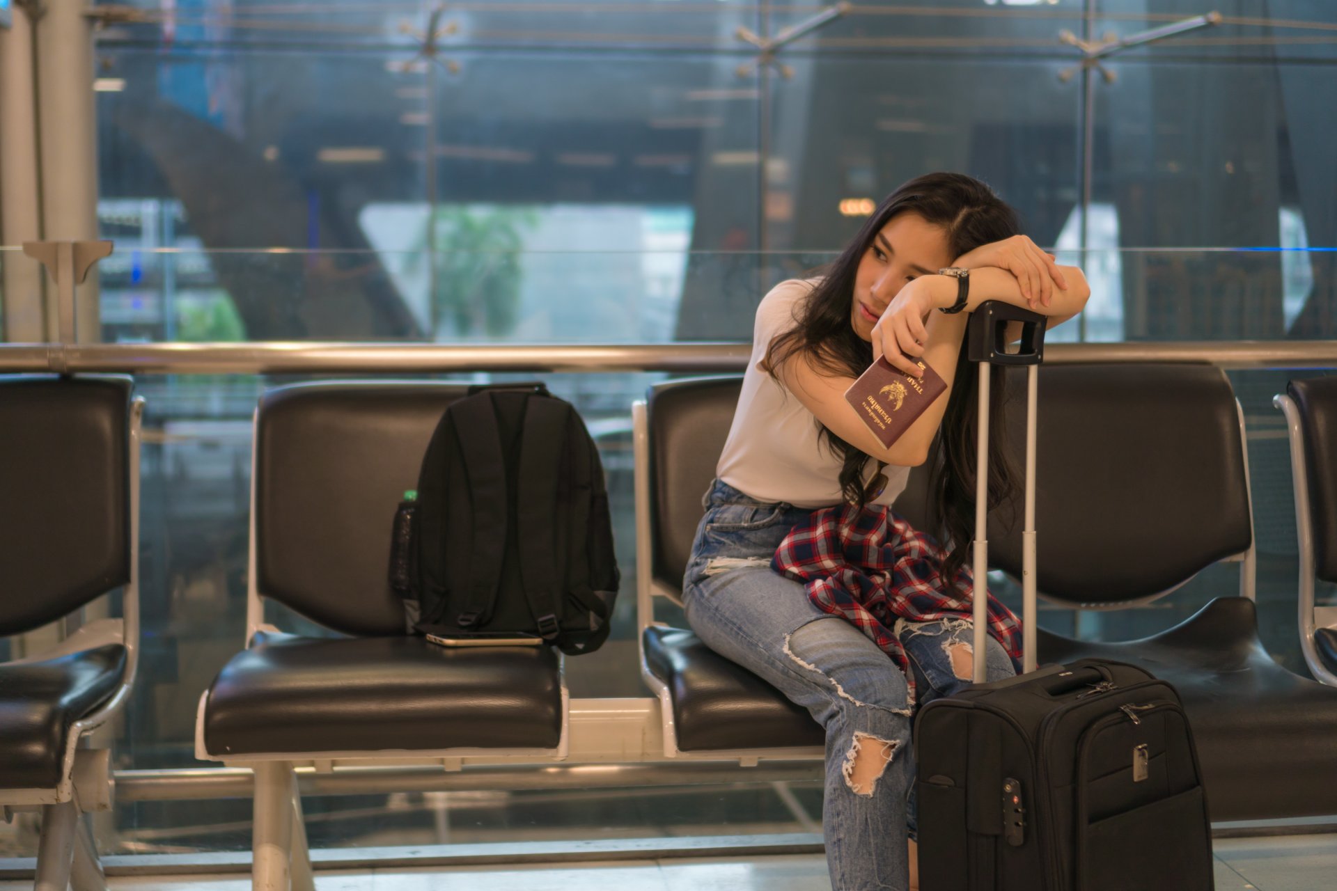 Wait for a friend to travel to the airport.
Her expression seemed boring. In her hand hold a passport.
Copy space.